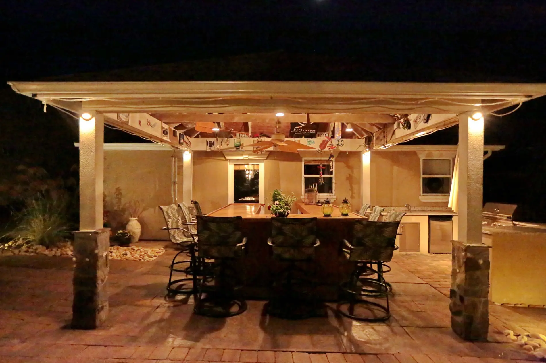 Covered outdoor kitchen and pergola lit for evening use